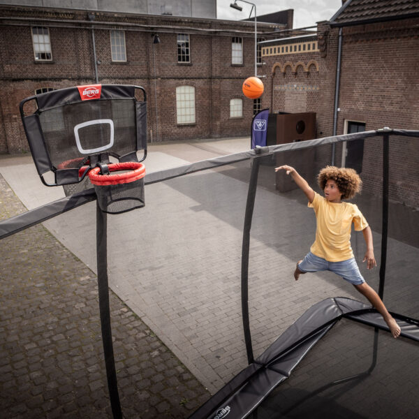 dítě házející míč na zavěšený koš na trampolíně