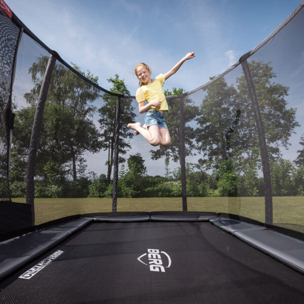 skákající dítě na trampolíně obdelníkového tvaru s ochrannou sítí